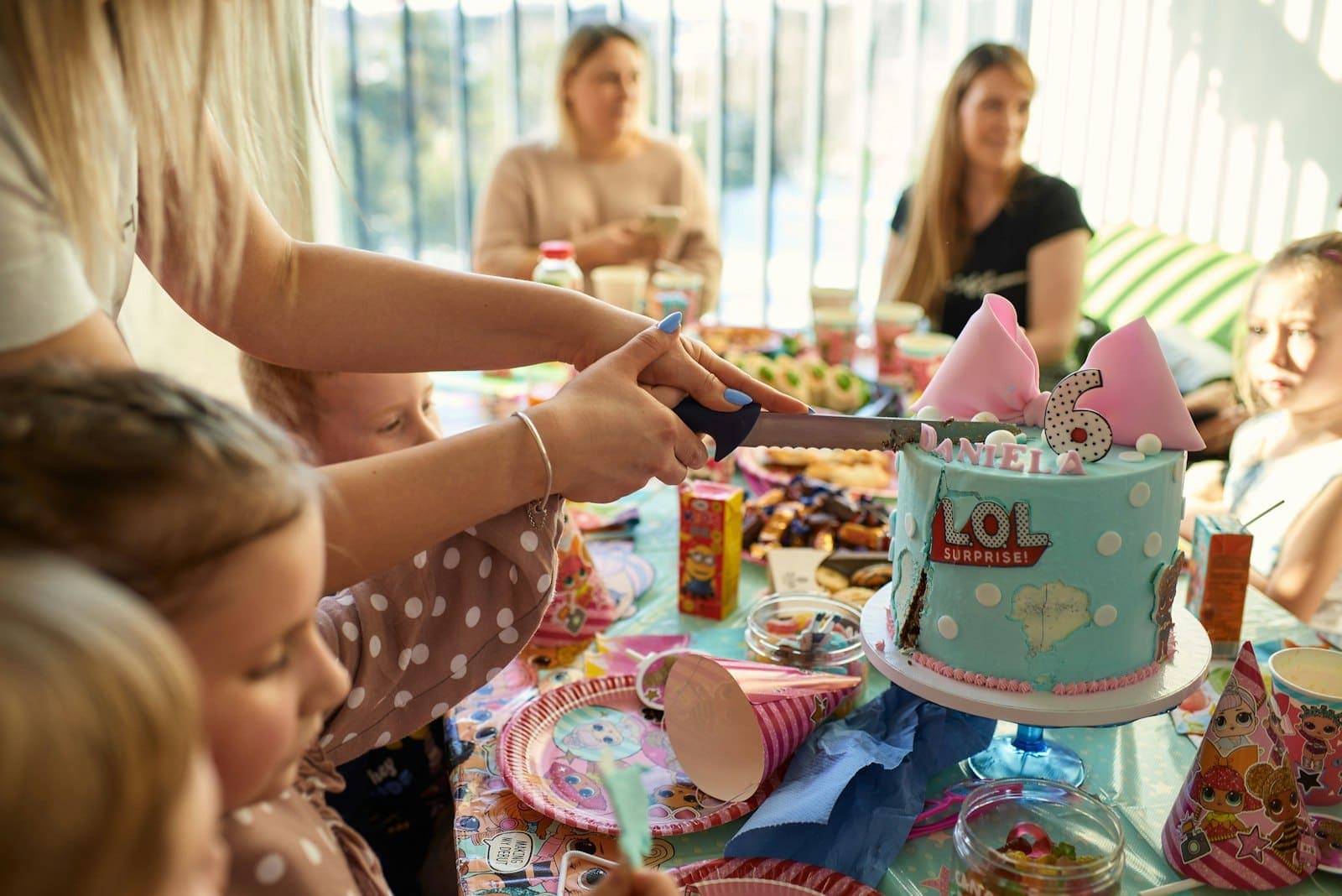 Une maman coupe le gâteau d’anniversaire devant les enfants assis autour de la table